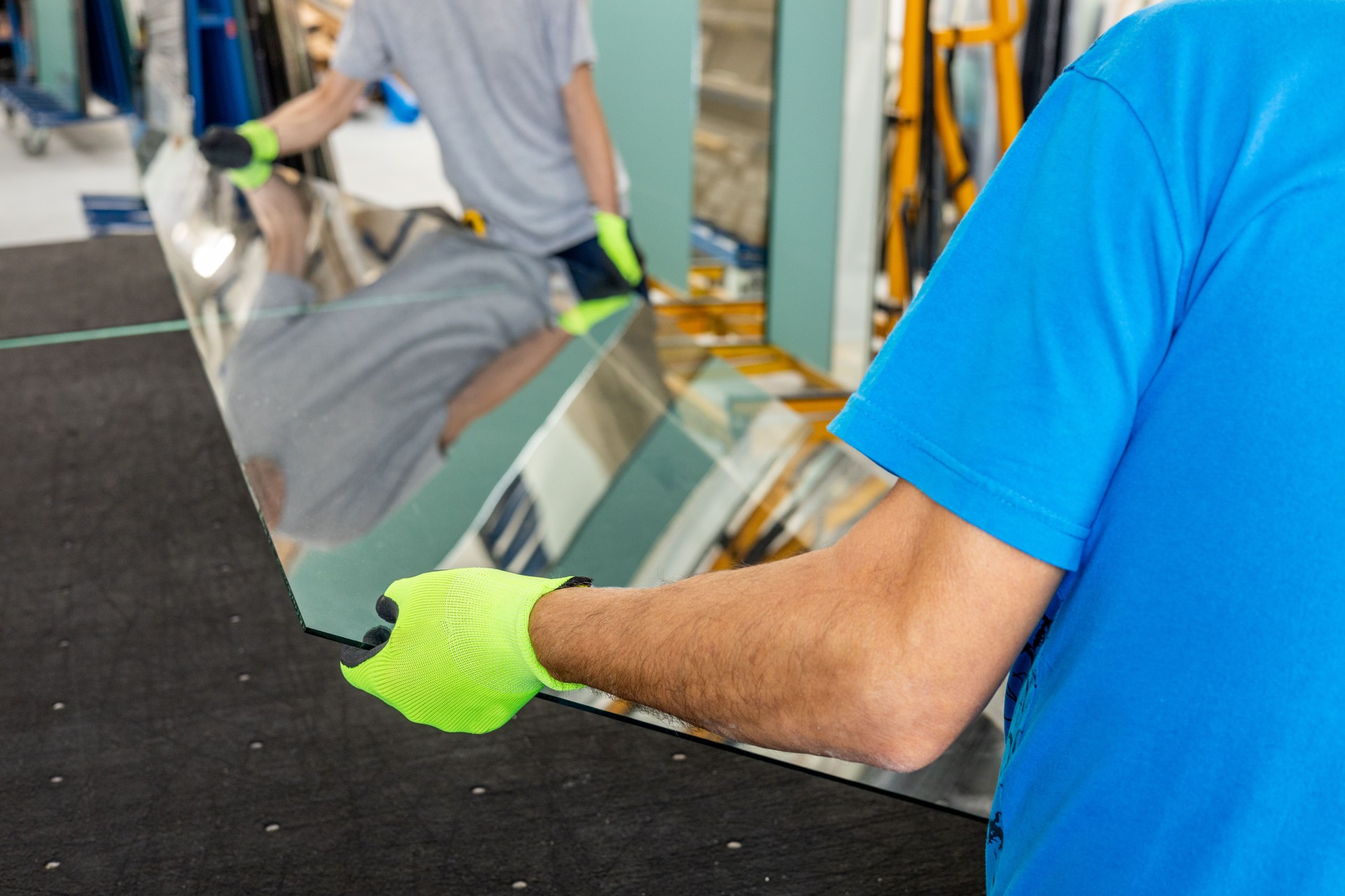 Glaziers place a large sheet of thick glass on the table by hand. Glass work